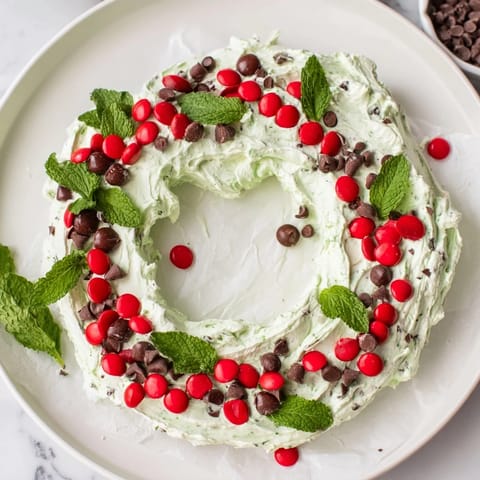 Festive Mint Chocolate Chip Dip Wreath, a creamy dessert decorated with red candies and fresh mint.