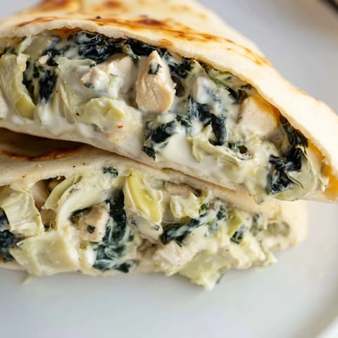 Gefüllte Pita Brote mit Hähnchen, Spinat und Artischocken, serviert warm und knusprig.