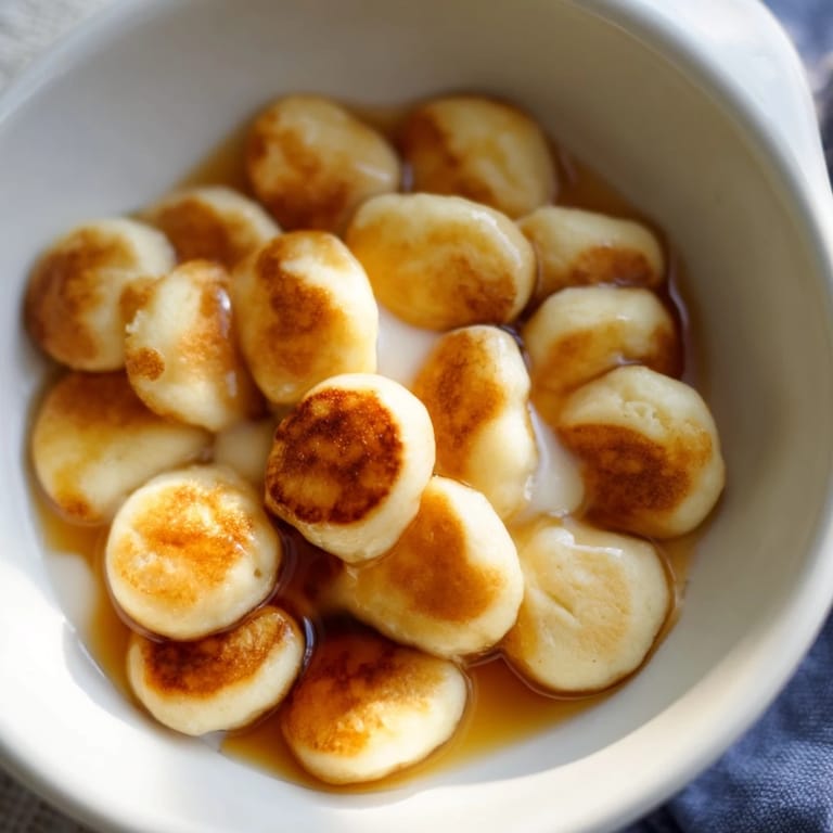 Warm, bite-sized fluffy pancake cereal with maple syrup and milk, ideal for brunch.