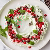 Festive Mint Chocolate Chip Dip Wreath, a creamy dessert decorated with red candies and fresh mint.